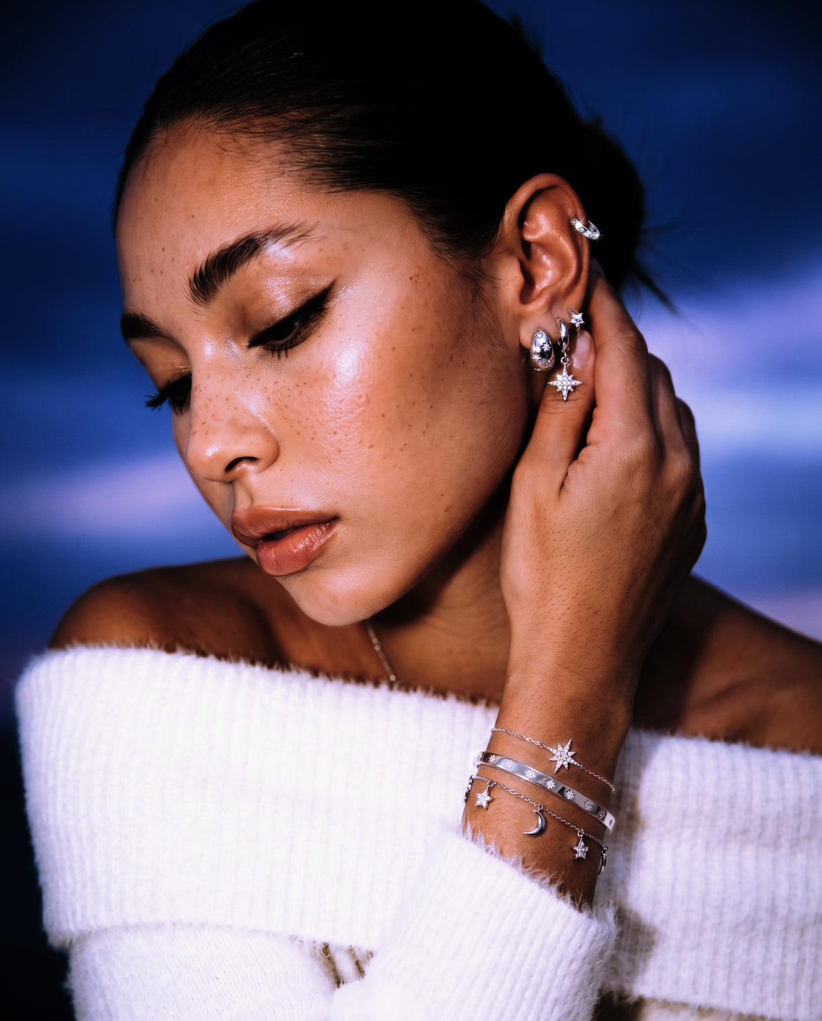 Silver star huggies, hoops and bracelets worn against a night sky