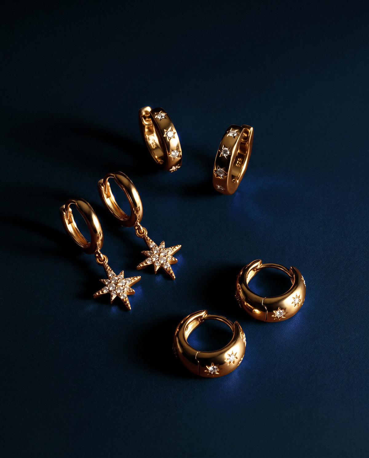 Gold star huggies and hoop earrings on midnight blue