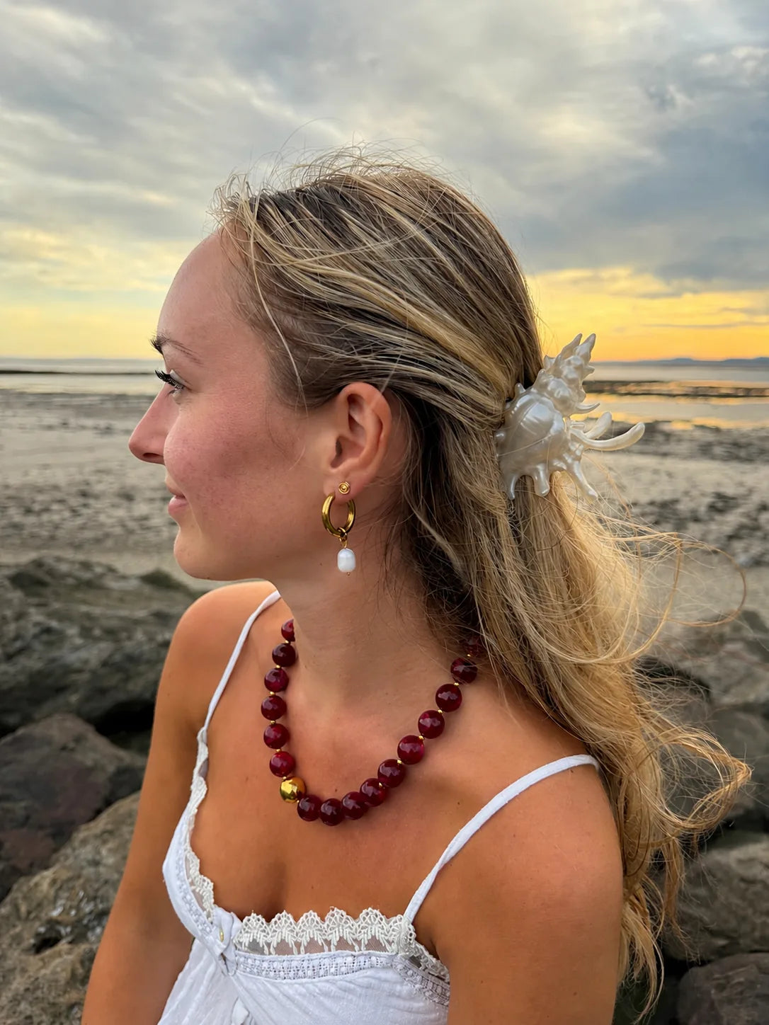 Burgundy beaded necklace and gold pearl hoops at sunset