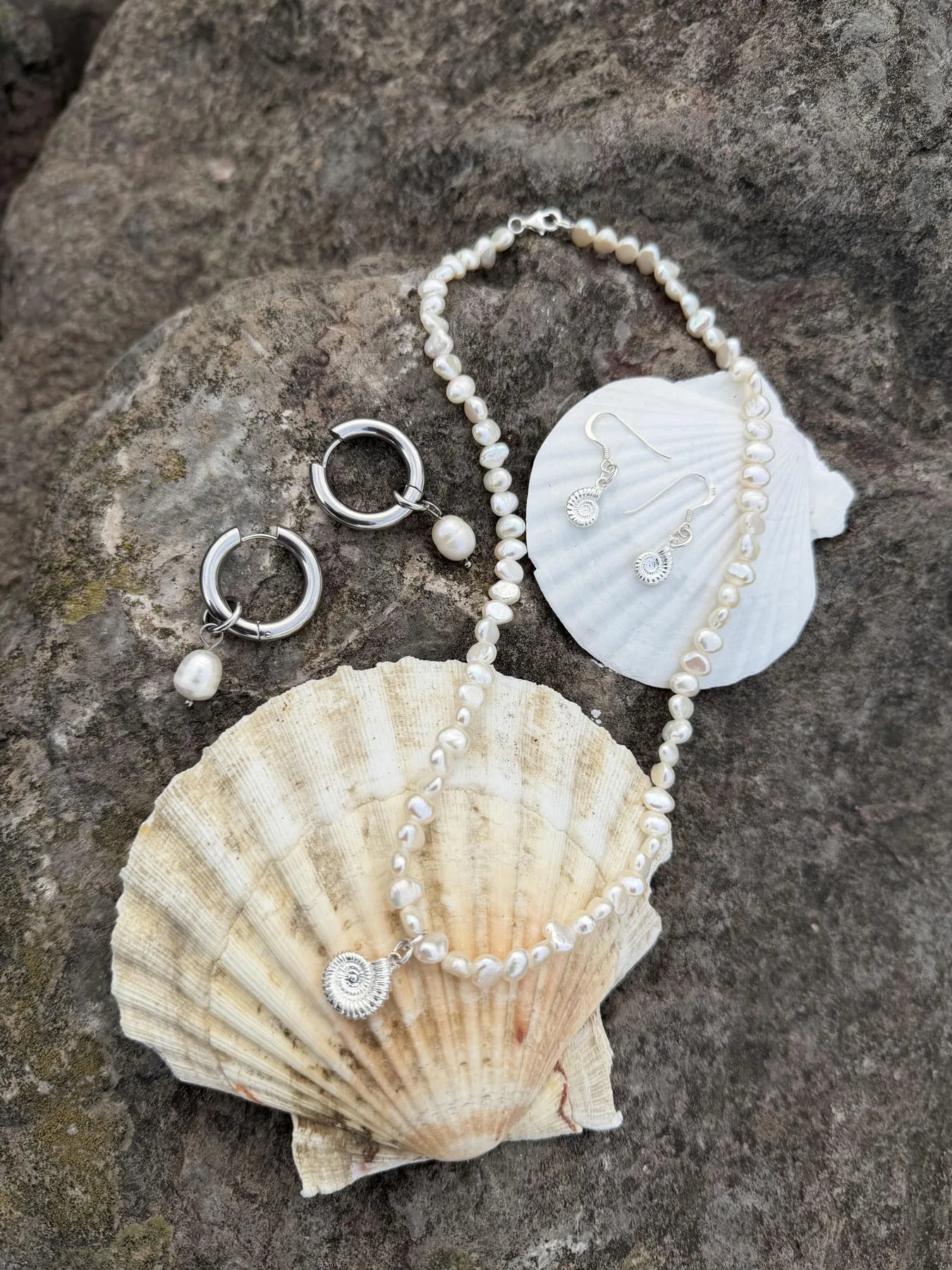 Pearl necklace, bracelet and silver ammonite earrings styled on sea shells