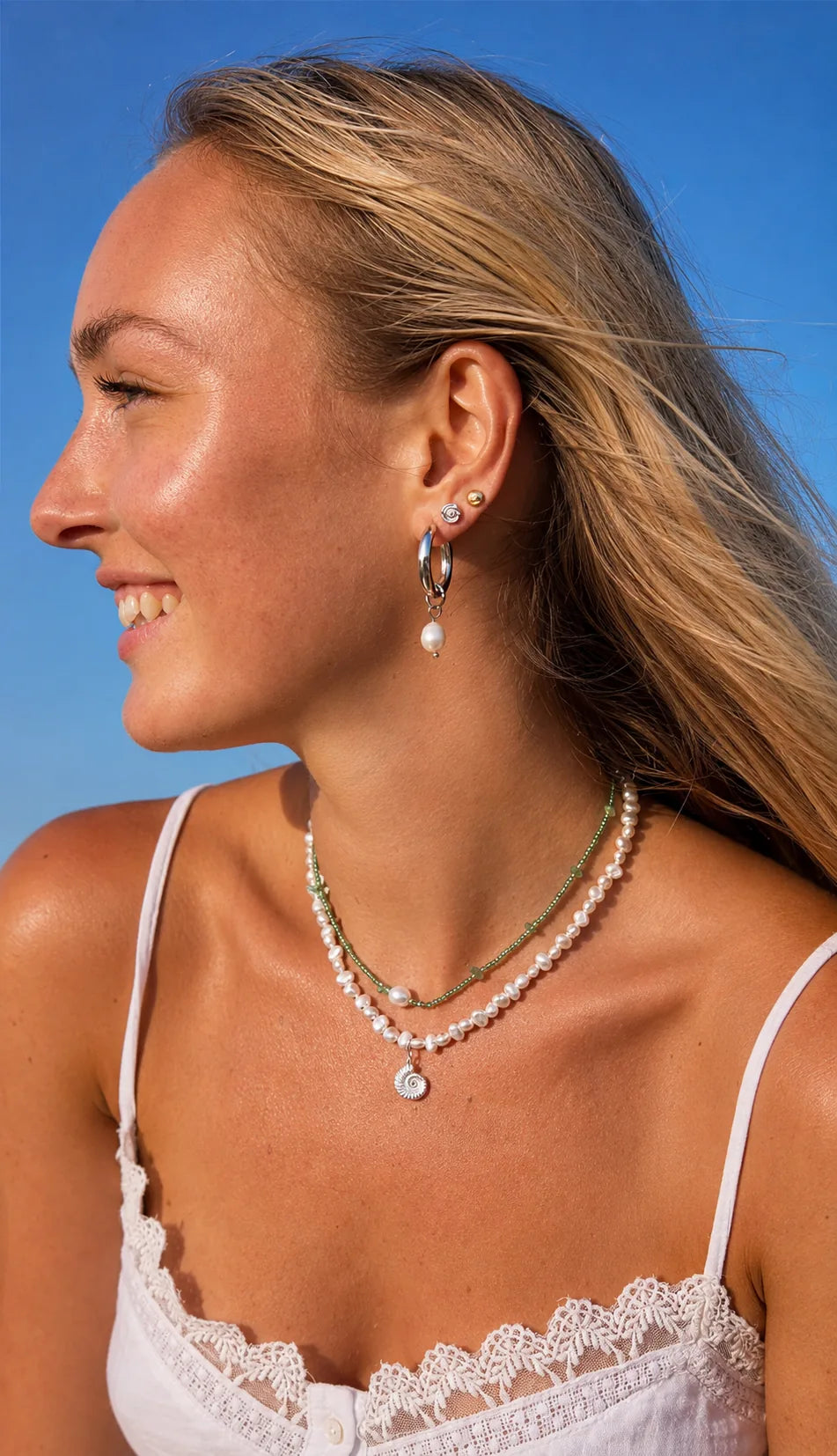 Layered green bead and pearl ammonite necklaces in summer sunshine