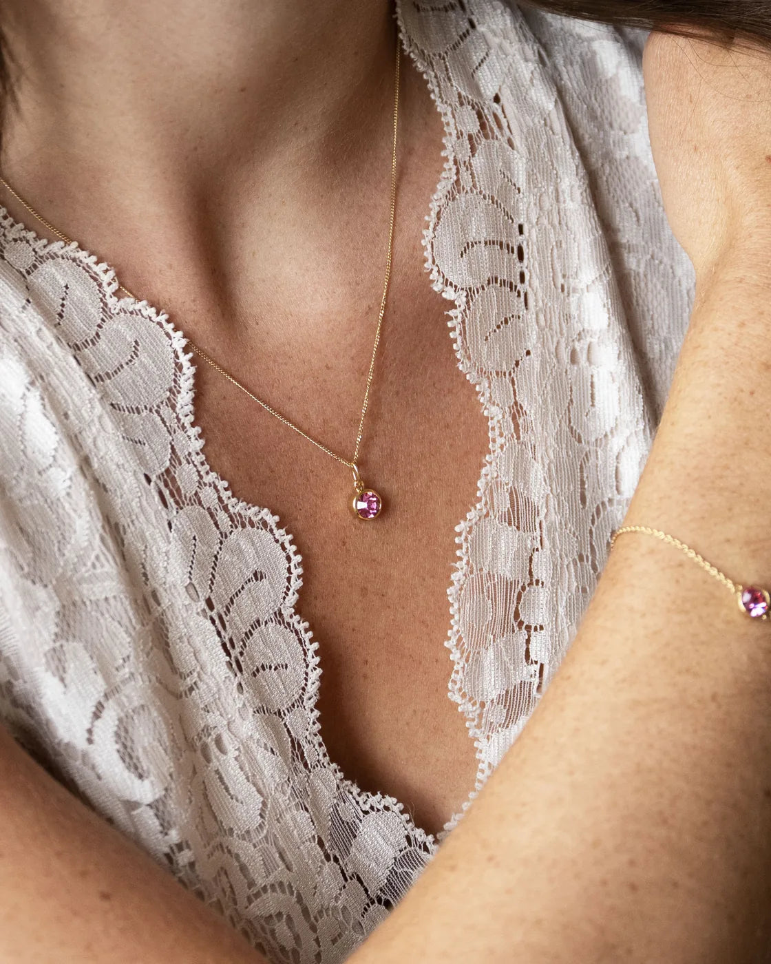 Gold October birthstone pendant and bracelet worn with lace