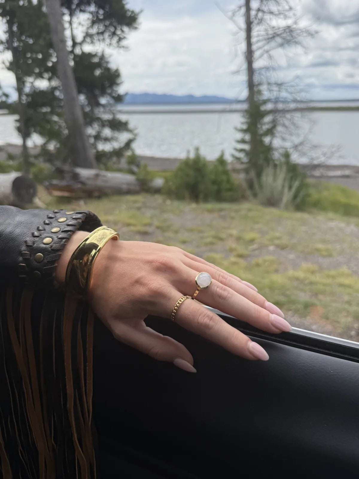 Moonstone ring, gold chain ring and bone cuff bangle by a Wyoming lake